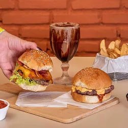 Dois hambúrgueres artesanais com batatas fritas, molhos e milk-shake de chocolate