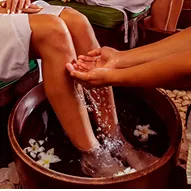 Woman lying on a table receiving a massage from a massage therapist.
