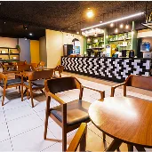 Espaço de bar moderno com balcão iluminado, cadeiras de madeira e mesas organizadas