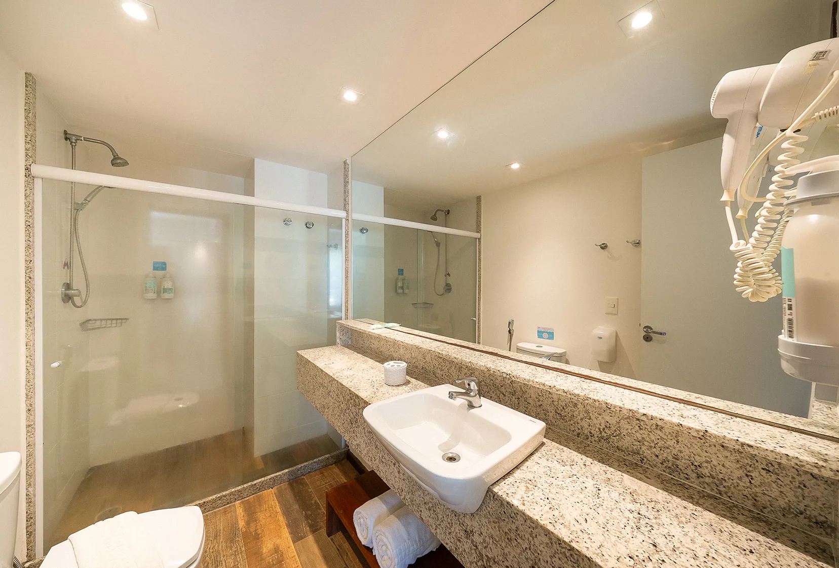 Banheiro da acomodação Suíte Familiar, com área para banho, chuveiro com regulagem da temperatura, pia, vaso, toalhas, secador de cabelo e amenities O Boticário.
