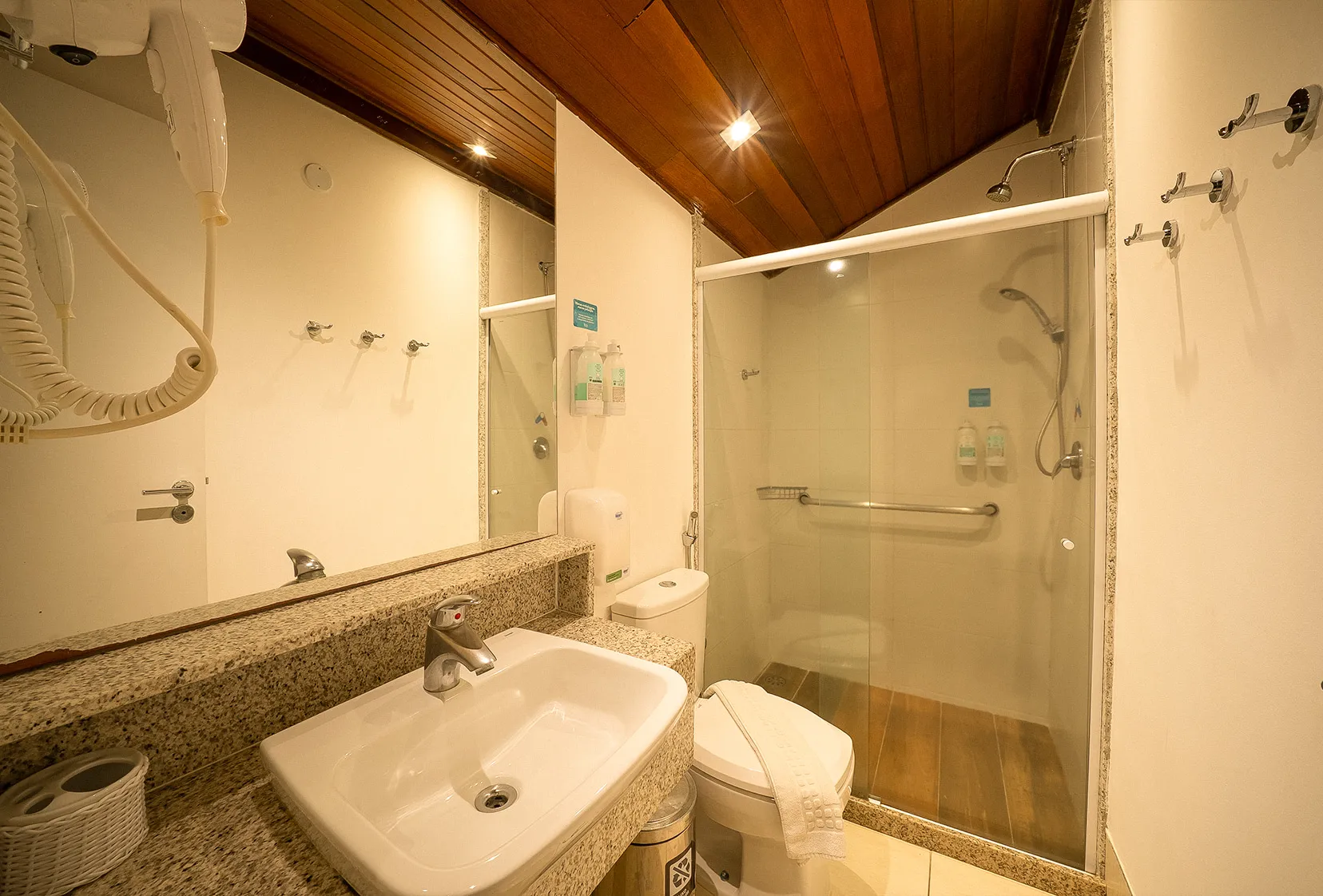 Banheiro do primeiro andar da acomodação Suíte Familiar, com área para banho, chuveiro com regulagem da temperatura, pia, vaso, toalhas, secador de cabelo e amenities O Boticário.