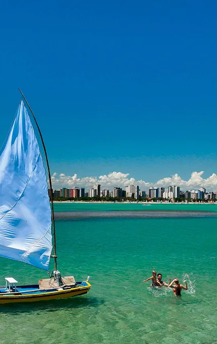 Vista das águas cristalinas e jangada em Maceió com a cidade ao fundo