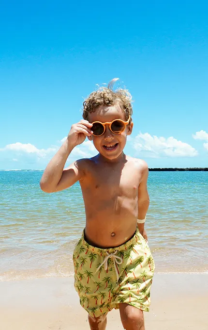 Criança sorridente aproveitando dia ensolarado na praia