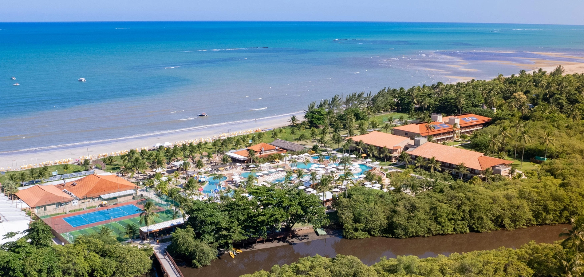 Vista aérea da estrutura completa do Salinas Maragogi All inclusive Resort à beira-mar da praia de Maragogi e cortado pelo Rio Maragogi, com piscinas, pontos de consumo, áreas de lazer e acomodações.