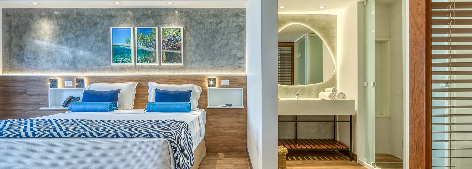 Apartamento Standard Vitória-Régia, uno de los alojamientos en Salinas Maragogi, con cama queen-size, baño y una acogedora decoración con madera, lámparas y una composición de pinturas de las playas de Maragogi.