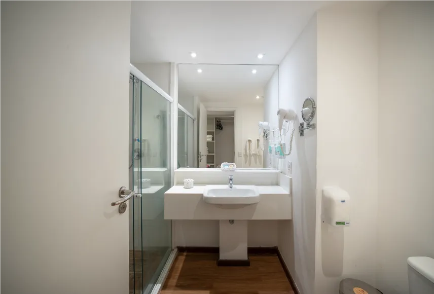 Baño del alojamiento Playa Jardín, con zona de baño, sanitarios, ducha con control de temperatura, decoración, artículos de aseo O Boticário, toallas, espejo grande y secador de pelo.