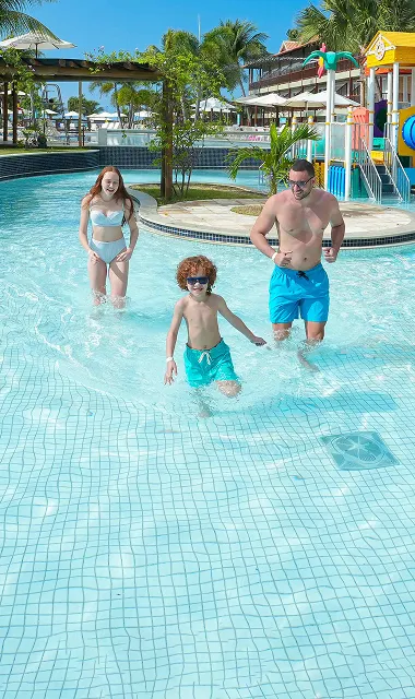 Criança e adulto praticando arvorismo em meio à natureza dentro de resort.