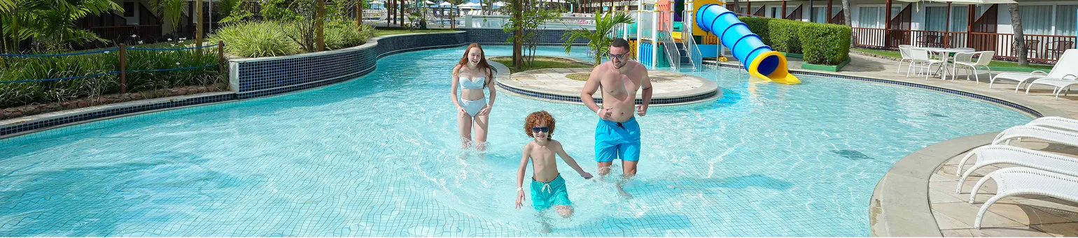 Criança e adulto praticando arvorismo em meio à natureza dentro de resort.