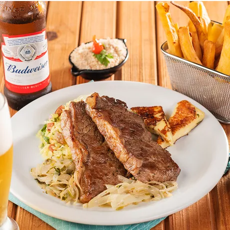 Prato com carne grelhada, queijo, arroz, batata frita, farofa, vinagrete e cerveja gelada
