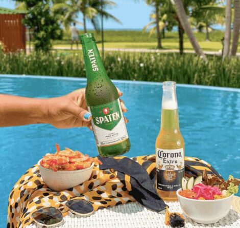 Mesa à beira da piscina com cervejas e petiscos servidos no clima descontraído de um resort All Inclusive em Alagoas.