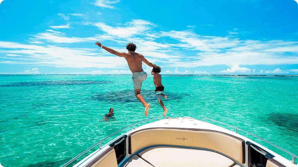 Pai e filho aproveitando o mar azul em um passeio de barco durante viagem em família.