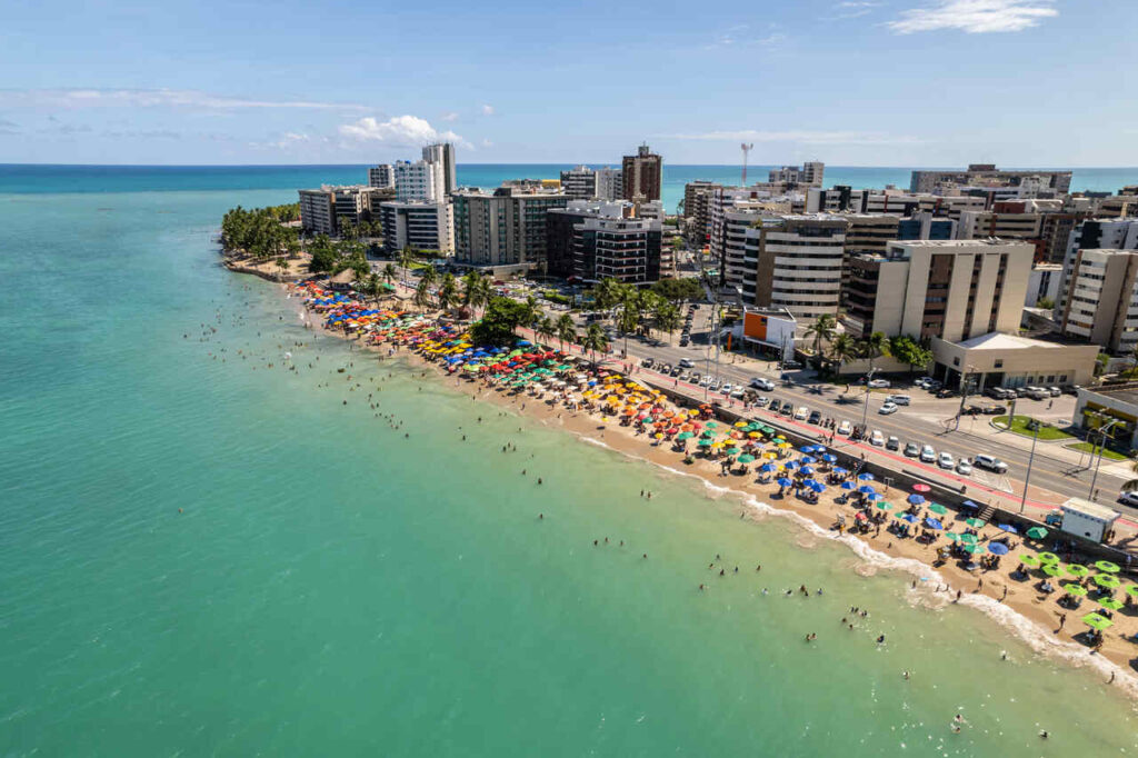 Imagem aérea de cidade à beira-mar, representando qual cidade escolher: Maragogi ou Maceió.