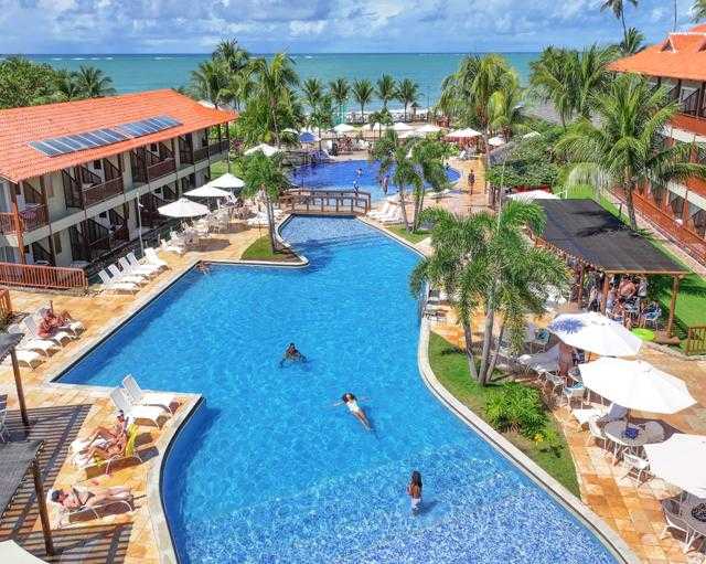 Imagem aérea da área principal do resort Salinas Maceió, com piscinas, acomodações, espaço de lazer e a praia ao fundo.