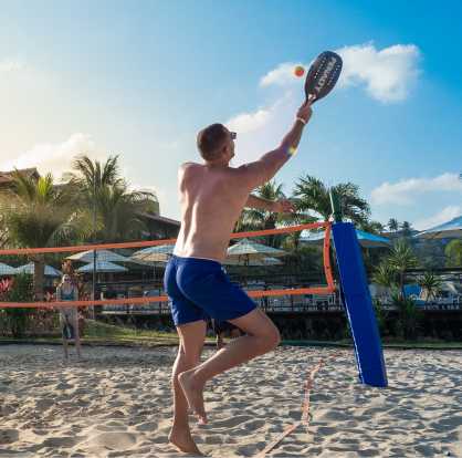 esportes todos idades Amigos jogando beach tennis na quadra de areia. Está no fim de tarde e tem algumas nuvens.
