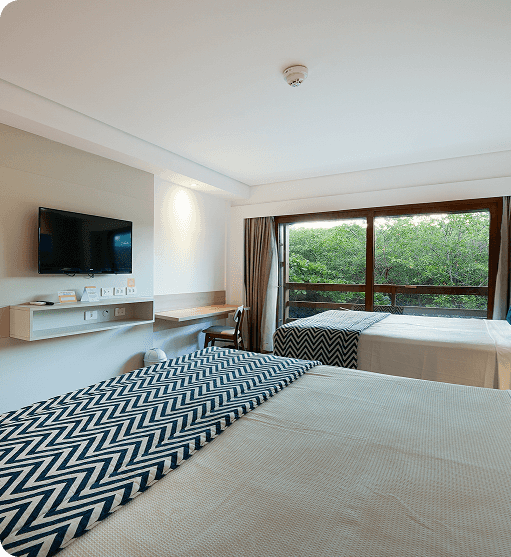 apartamento superior Quarto Apartamento Superior no Salinas Maceió destacando a vista externa pra o jardim e coqueiros próximos à área de lazer.