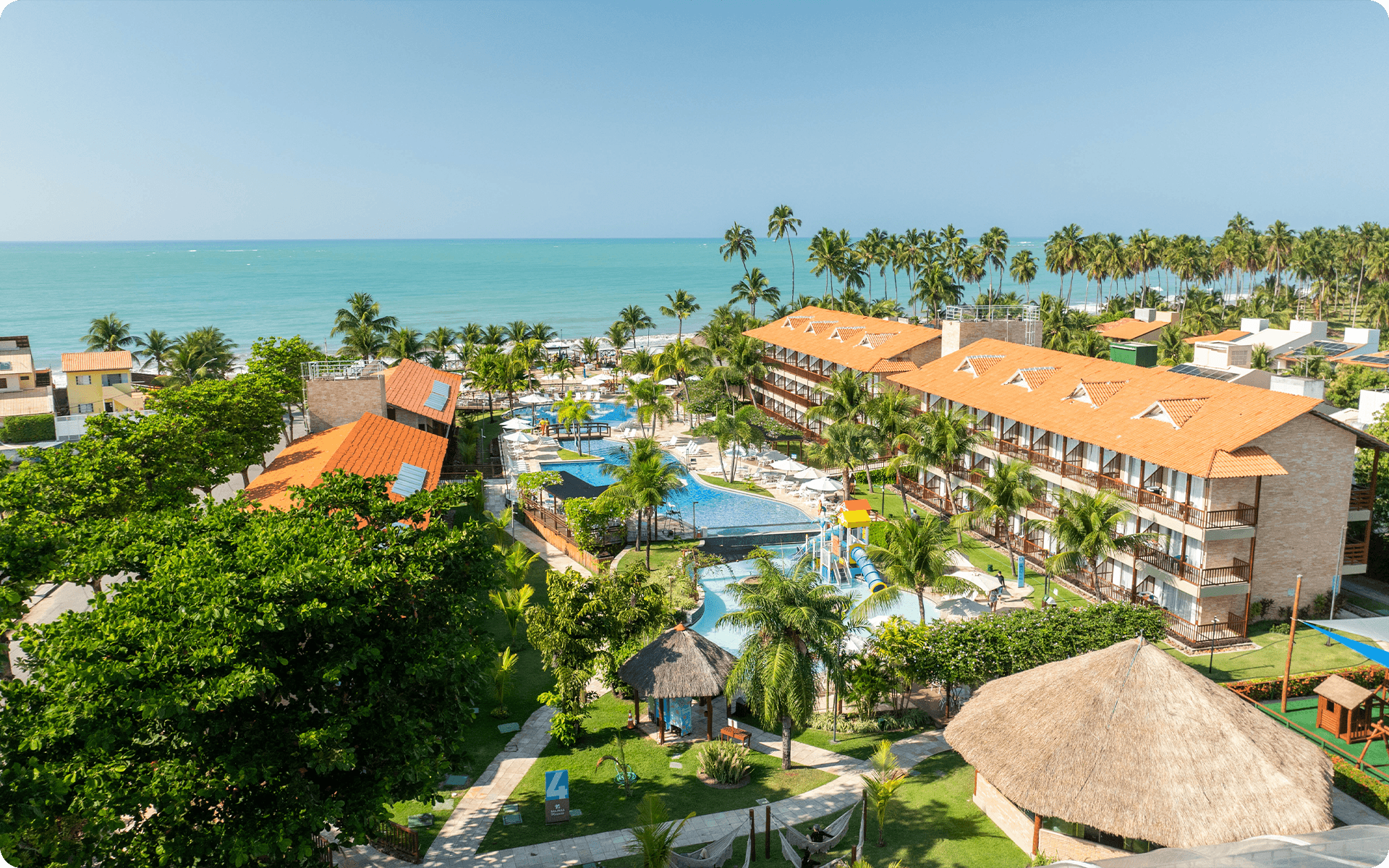 Vista áerea do Salinas Maceió, mostrando complexo de piscinas, quartos, área de lazer e ao fundo a grande imensidão da praia.