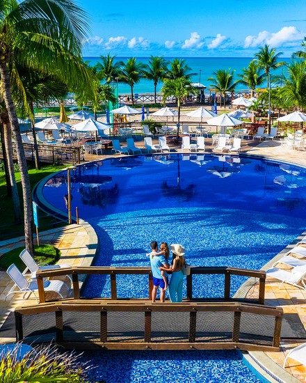 A estrutura completa do Salinas Maceió All Inclusive Resort vista do alto. Vista aérea do resort Salinas Maceió. A área de lazer tem piscinas interligadas, coqueiros e escorregadores. Ao fundo, a praia com o mar azul-turquesa.