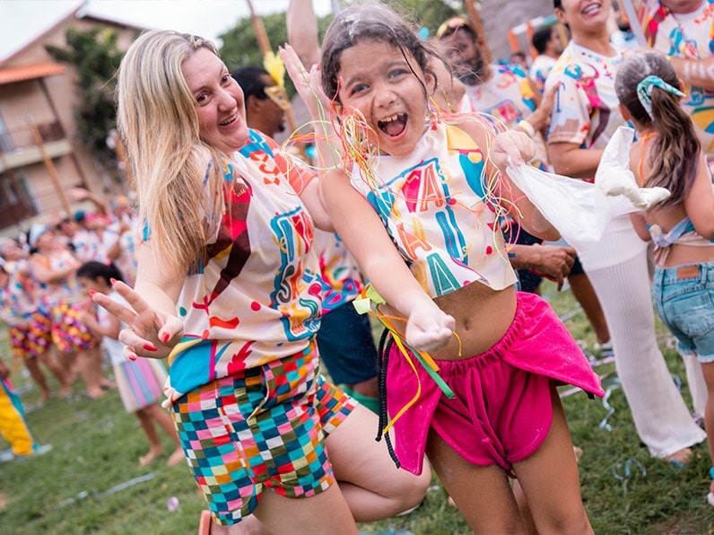 Mulher e criança vestidas com o abadá do bloco Viva Salinas posam pra foto sorrindo.