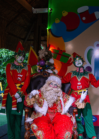Papei noel e dois duendes felizes durante entrega de presentes no natal no Salinas Maceió.