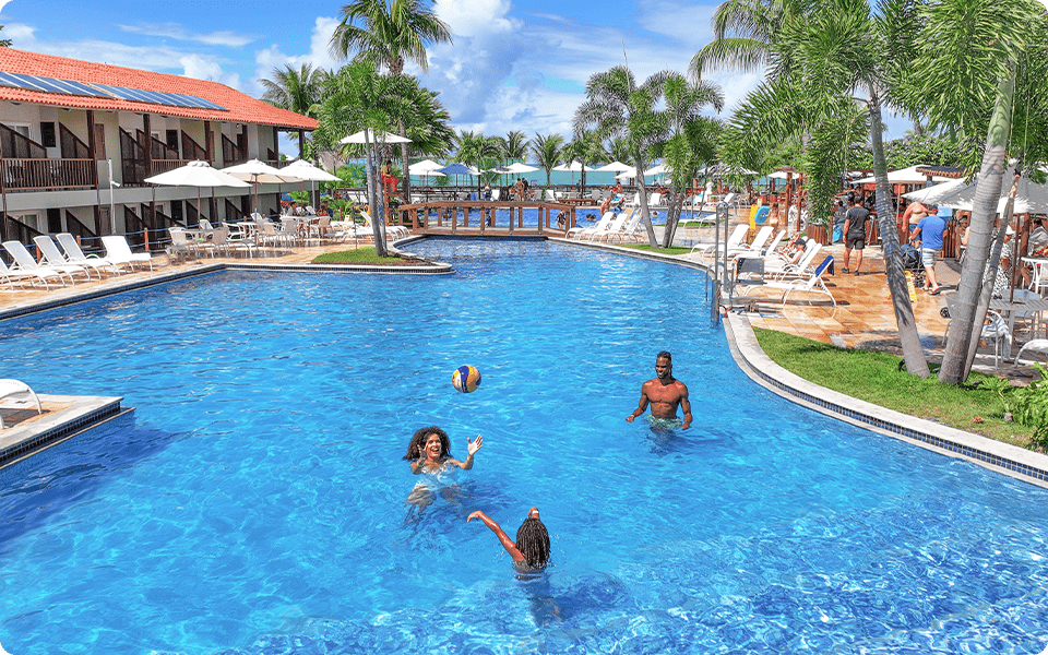 Família feliz jogando vôlei na piscina do Salinas Maceió.