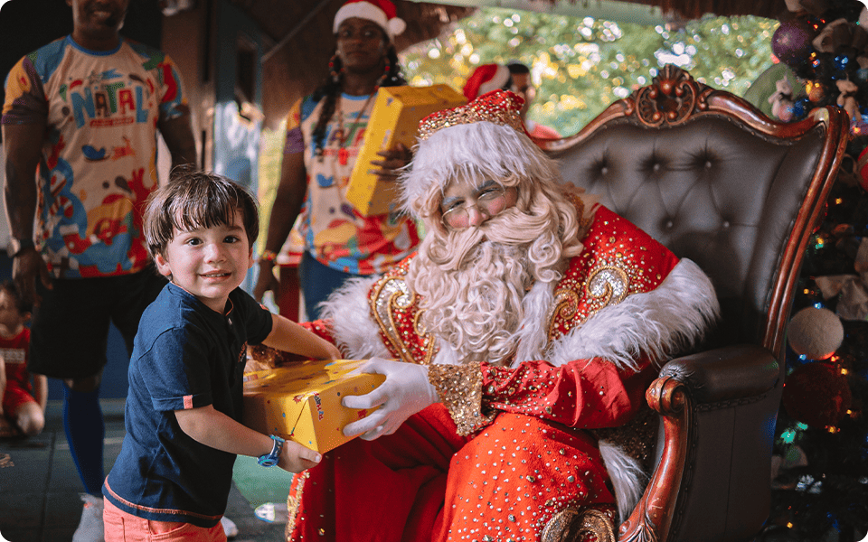 Papai Noel entregando presente a garotinho em festa de Natal no Salinas Maceió.