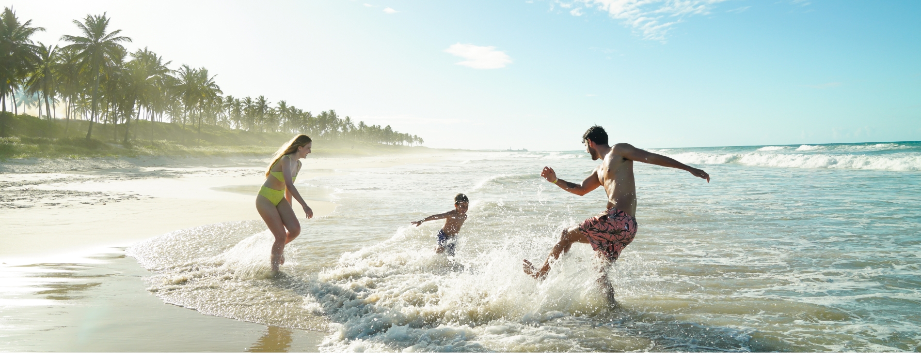 Casal e criança brincando na praia do Salinas Maceió, em dia ensolarado e com coqueiros ao fundo Casal e criança brincando na praia do Salinas Maceió, em dia ensolarado e com coqueiros ao fundo