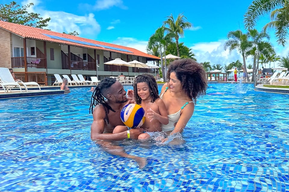 Família feliz curtindo banho de piscina no Salinas Maceió.