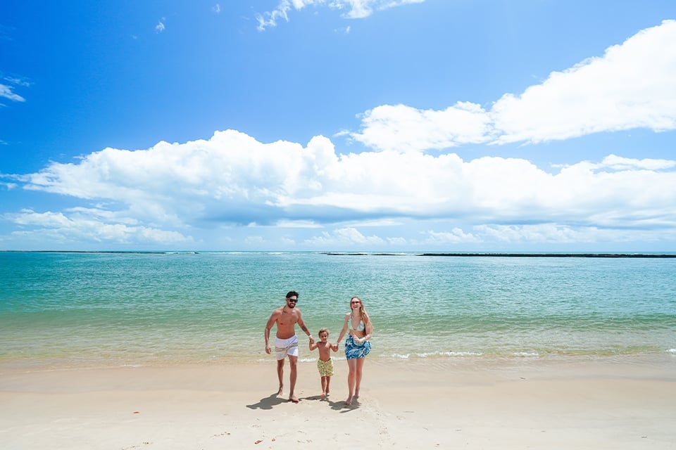 Família feliz curtindo dia ensolarado na beira do mar da praia do Gunga, em Alagoas.