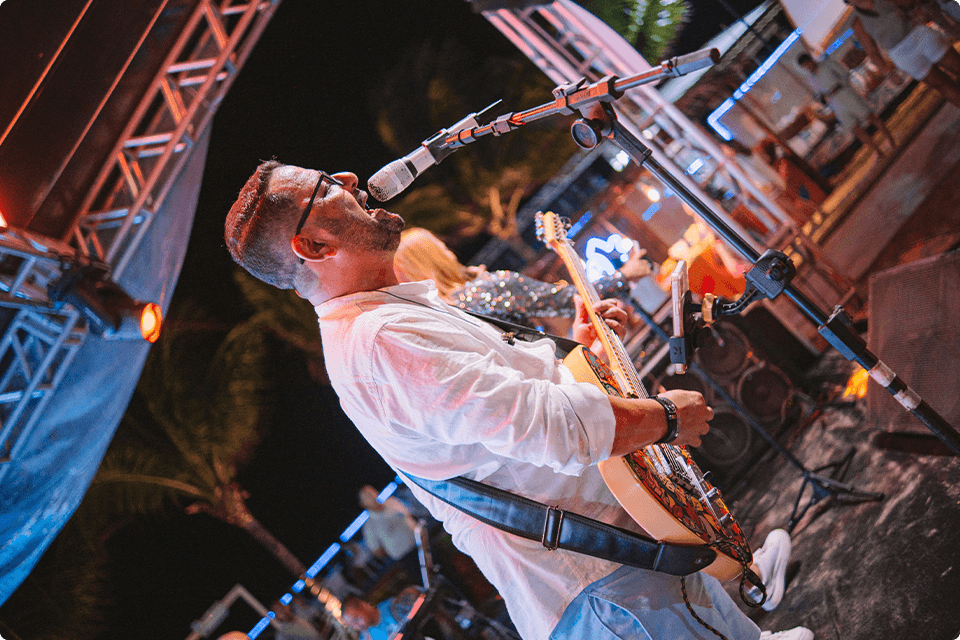 Músico cantando e tocando guitarra no palco durante a noite da festa de Réveillon.