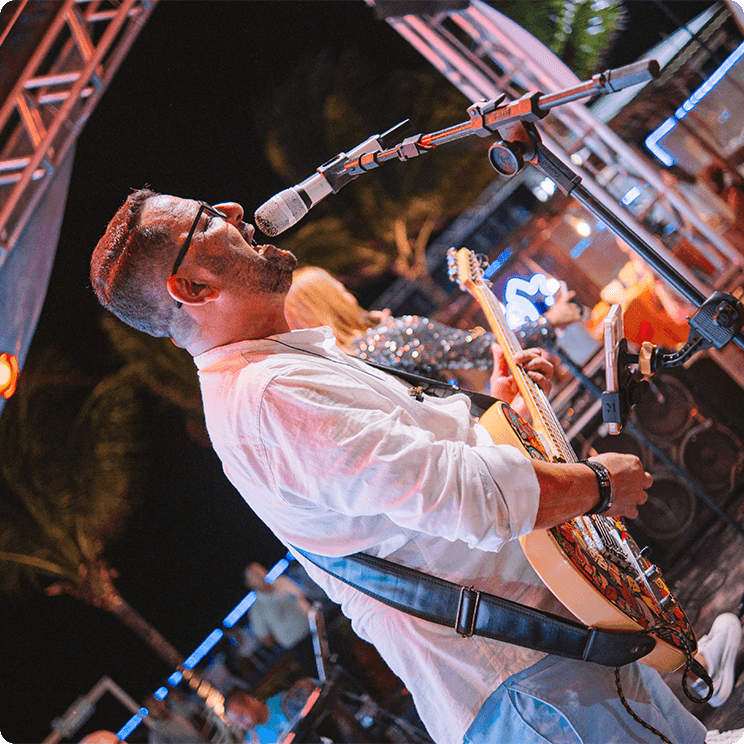 Músico cantando e tocando guitarra no palco durante a noite da festa de Réveillon.