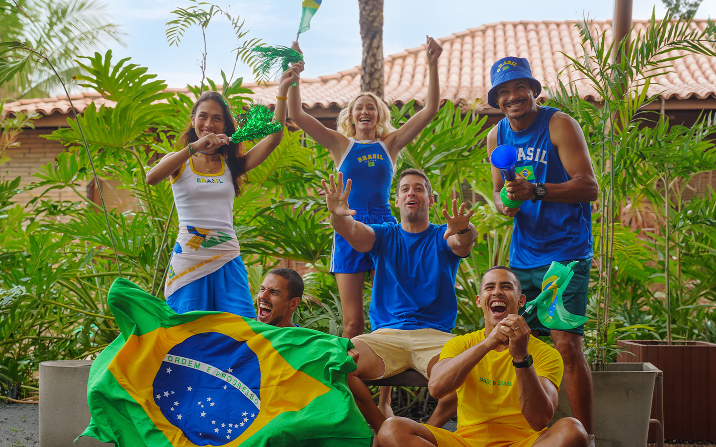 Todos unidos pra torcer pro Brasil Grupo de quinto amigos torcedores usando camisas do Brasil, segurando bandeiras e vuvuzela em clima de jogo no Salinas Maceió.