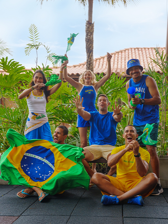 Todos unidos pra torcer pro Brasil Grupo de quinto amigos torcedores usando camisas do Brasil, segurando bandeiras e vuvuzela em clima de jogo no Salinas Maceió.