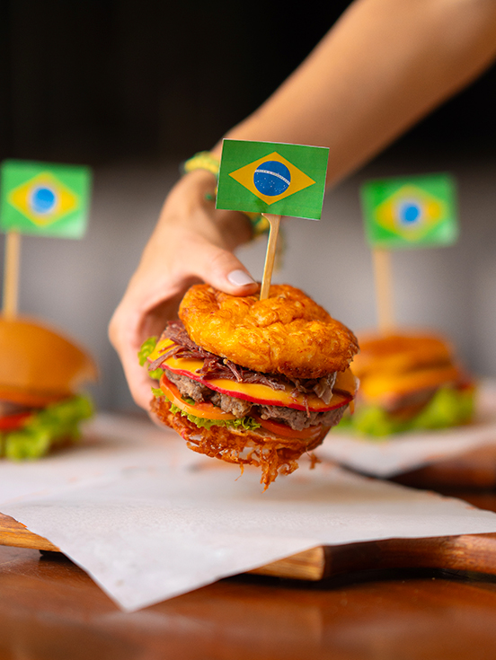 Hambúrguer artesanal com bandeira do Brasil no topo, servido em tábua de madeira no Salinas Maceió.