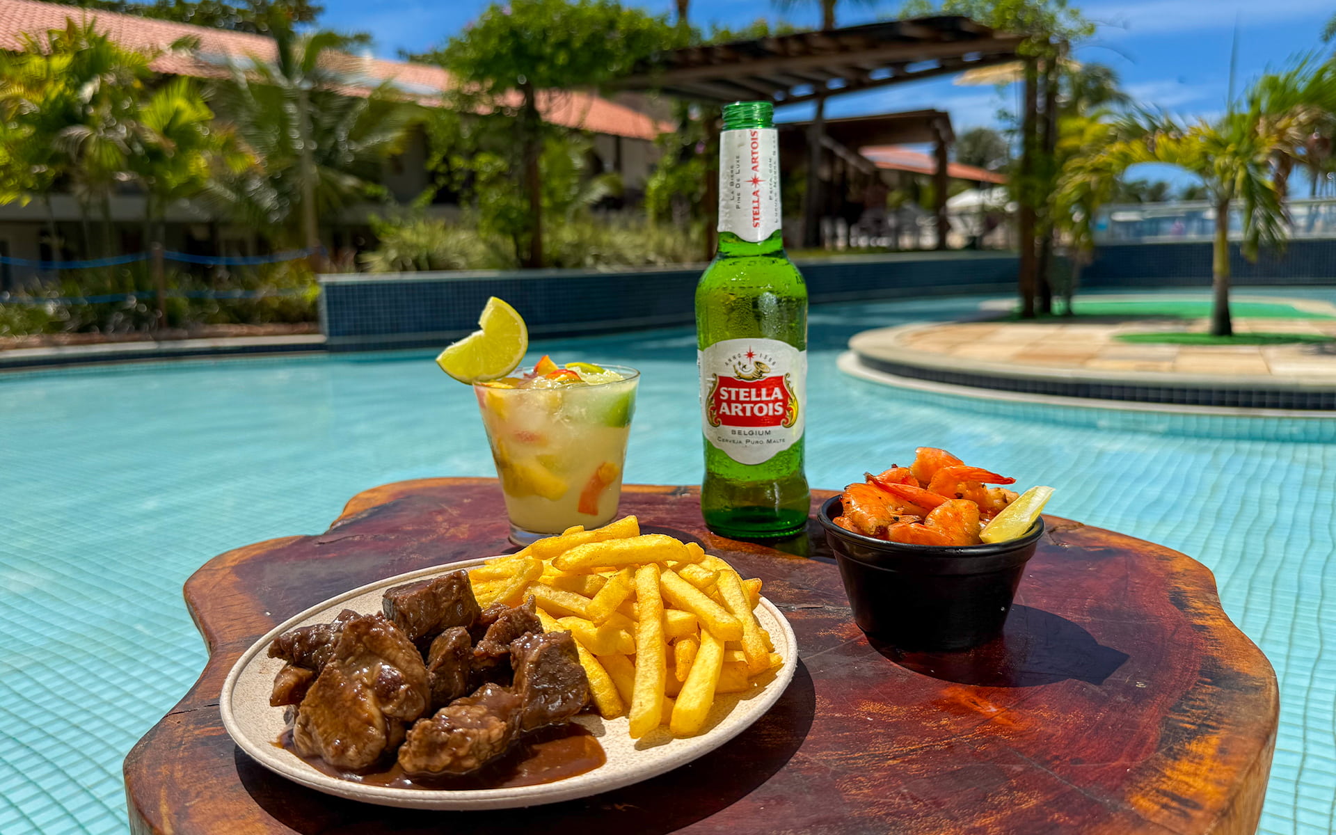 Prato com batata frita e carne, camarão, drink, cerveja Stella Artois servido à beira da piscina no Salinas Maceió.