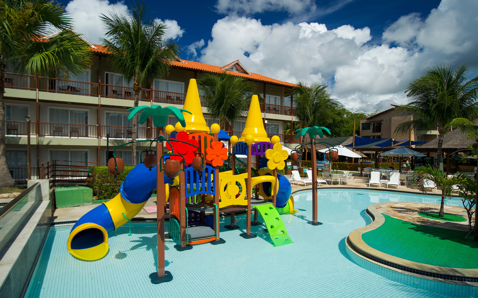 Área infantil aquática do Salinas Maceió com brinquedão pra crianças na piscina, e ao fundo toda a estrutura do resort.