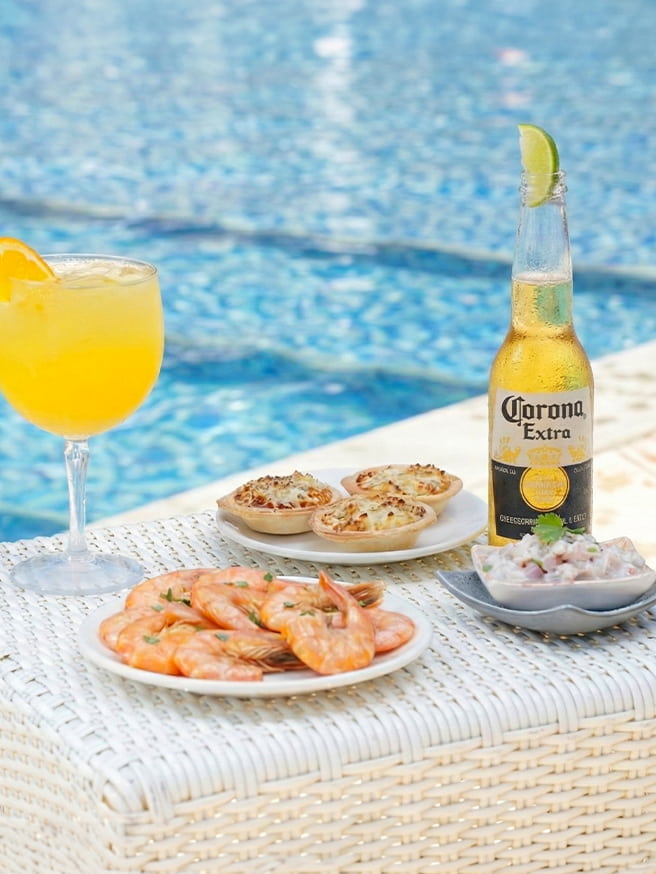 Drinks amarelo refrescantes, uma long neck da Corona e petiscos servidos na piscina do Salinas Maceió.