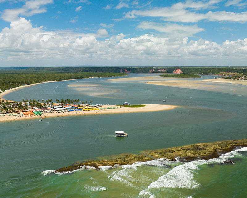Imagem aérea da Praia do Gunga, no Alagoas, com visualização da faixa de areia, barracas e mar aberto.