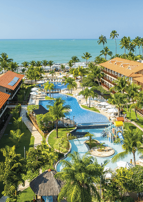 semana-do-consumidor-salinas-maceió-resort Vista aérea do Salinas Maceió, com bloco de apartamentos nas laterais, área de lazer com piscinas ao centro, com bastante coqueiros e áreas verdes. Ao fundo a praia de Ipioca.