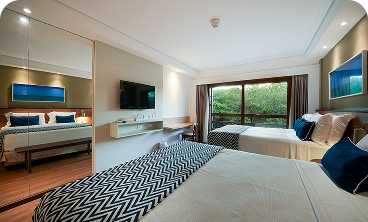 Casal e filho em Ponta de Mangue, o mar está com maré baixa e cristalino, ao fundo os arrecifes de corais.