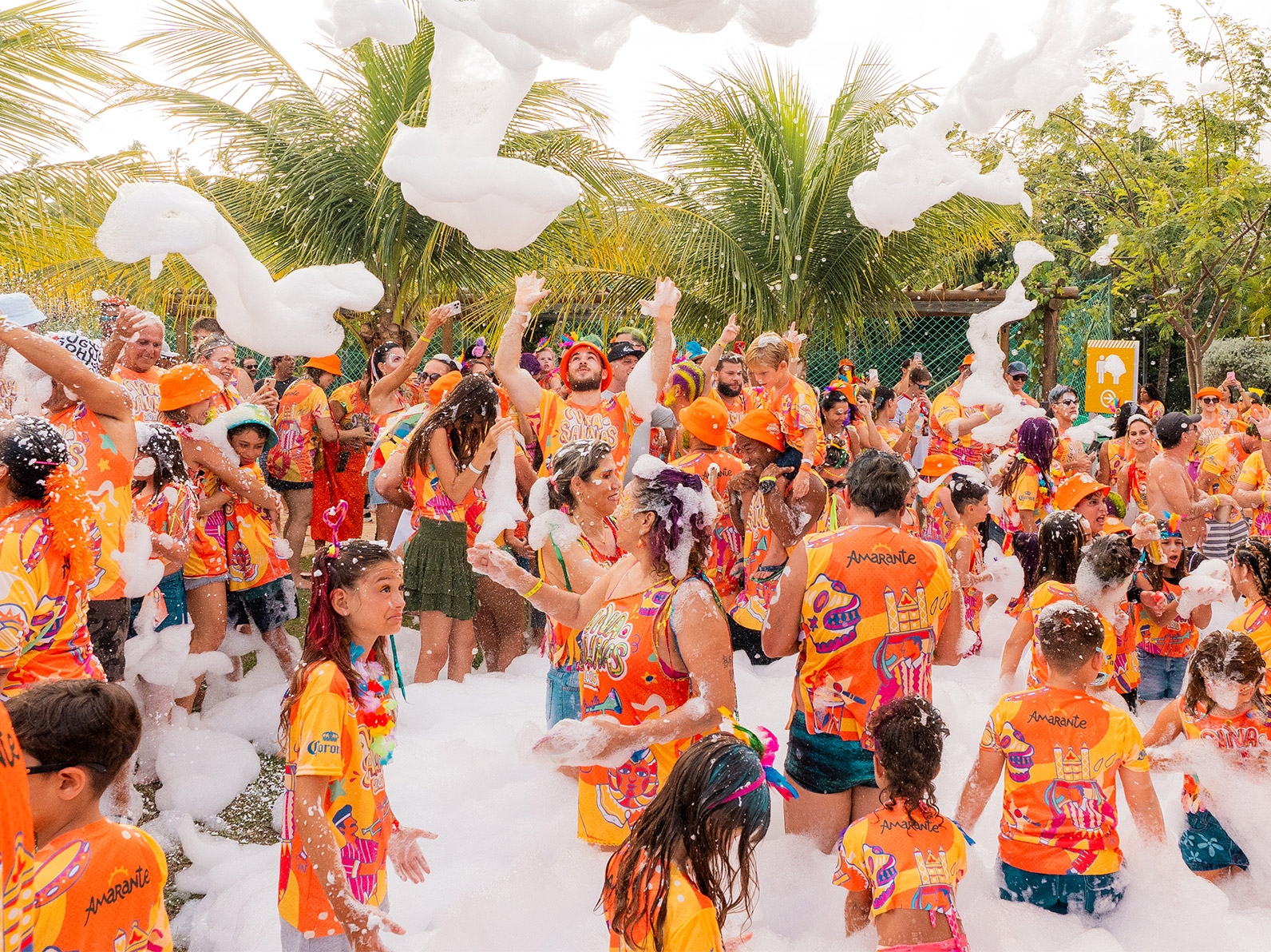 Hóspedes se divertindo na festa da espuma durante o Carnaval Salinas 2025 no Salinas Maragogi, com pessoas vestidas com abadás, com palmeiras ao fundo.