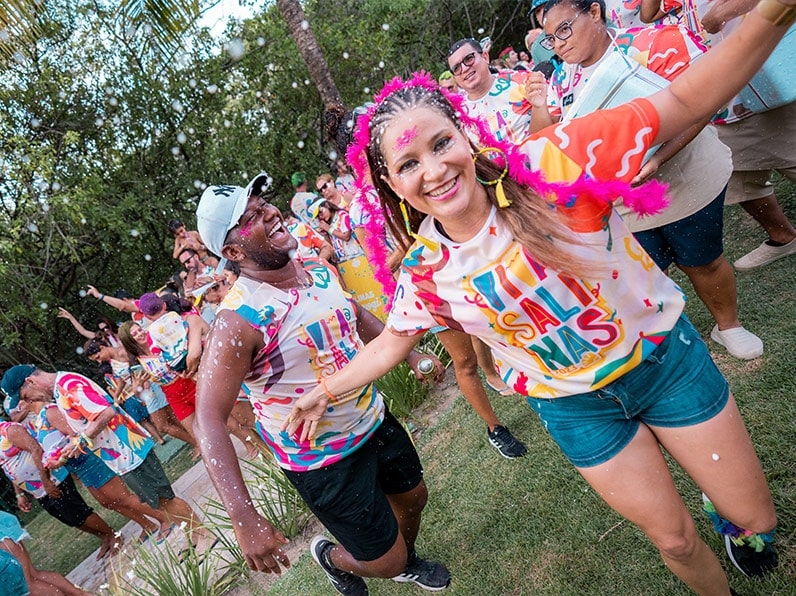 Mulher vestida com abadá do bloco Viva Salinas brinca carnaval com All Inclusive em Maragogi.