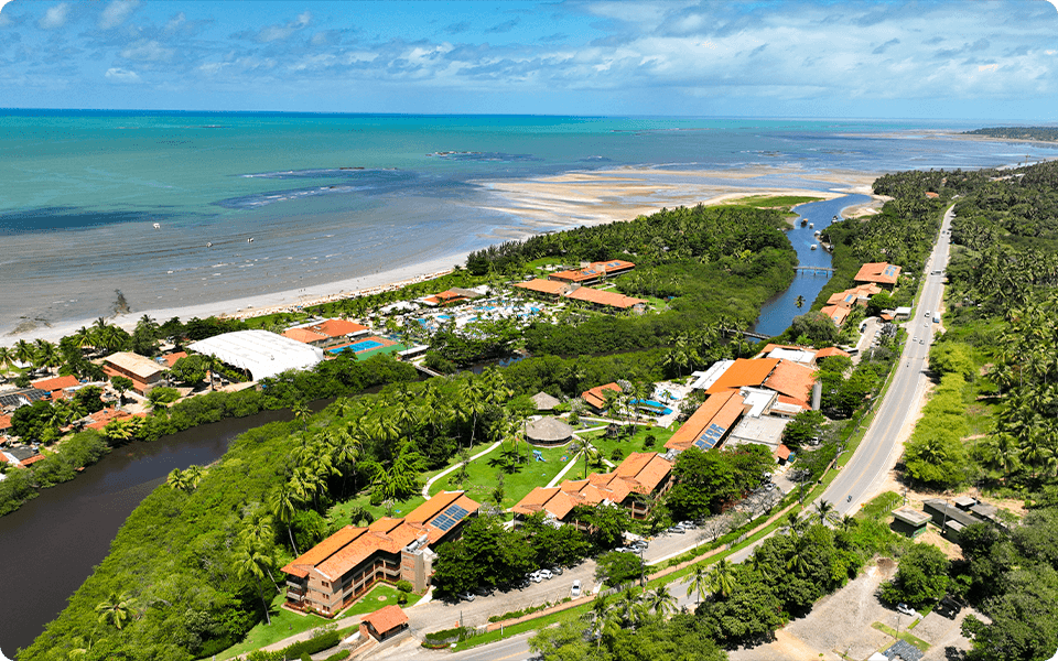 Vista aérea do Salinas Maragogi, mostrando os prédios, piscinas, área de lazer, o rio e o mar.