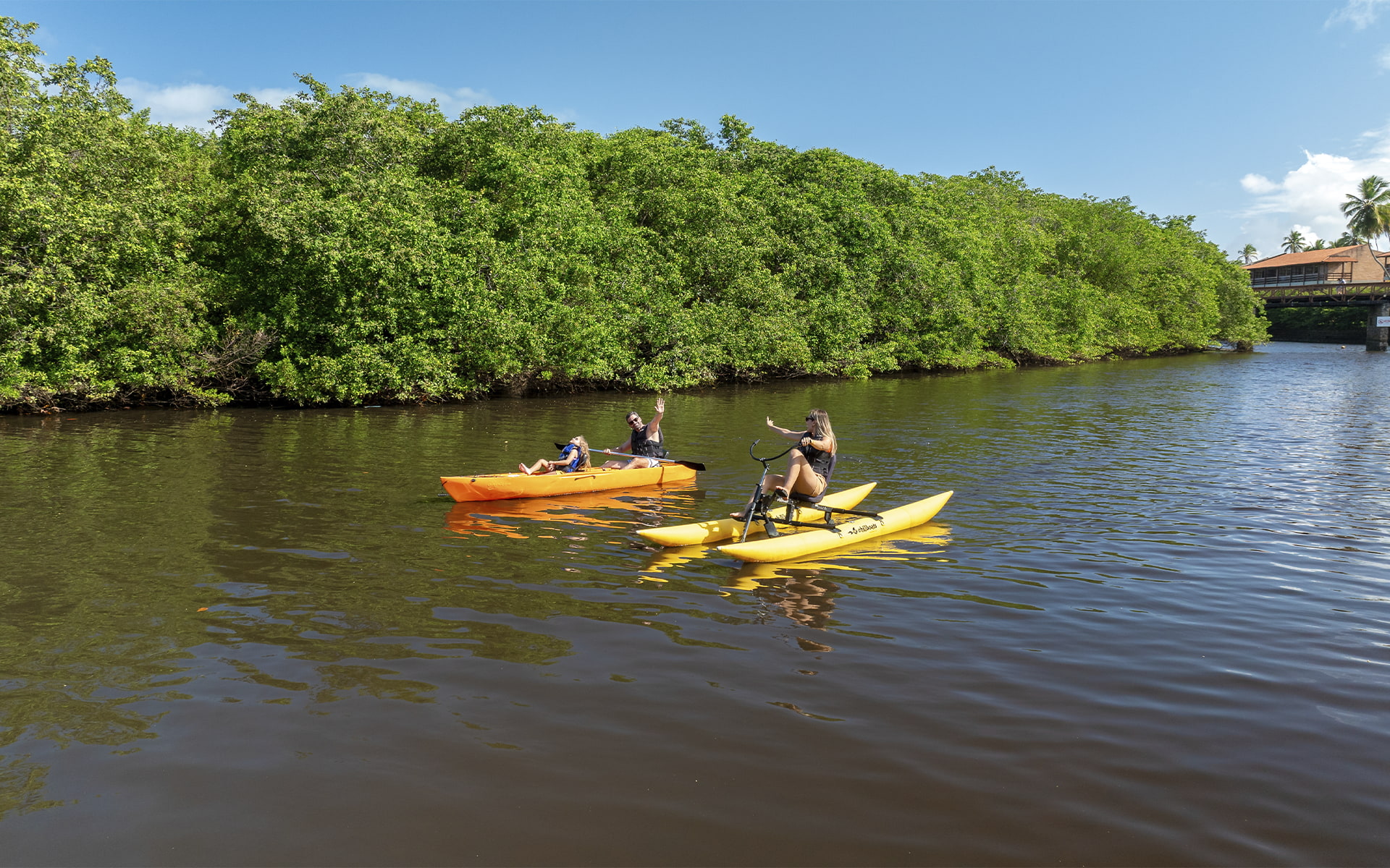 Aventuras fazem parte das férias de 2027 Família em passeio de caiaque pelo Rio Maragogi, cercado por vegetação de mangue nativa.