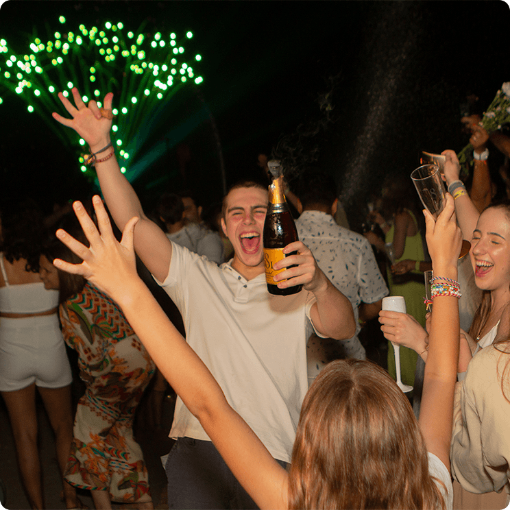 Família brindando o Reveillon com muita alegria. Taças e espumantes em mão para brindar, com fogos de artifício verde no céu.