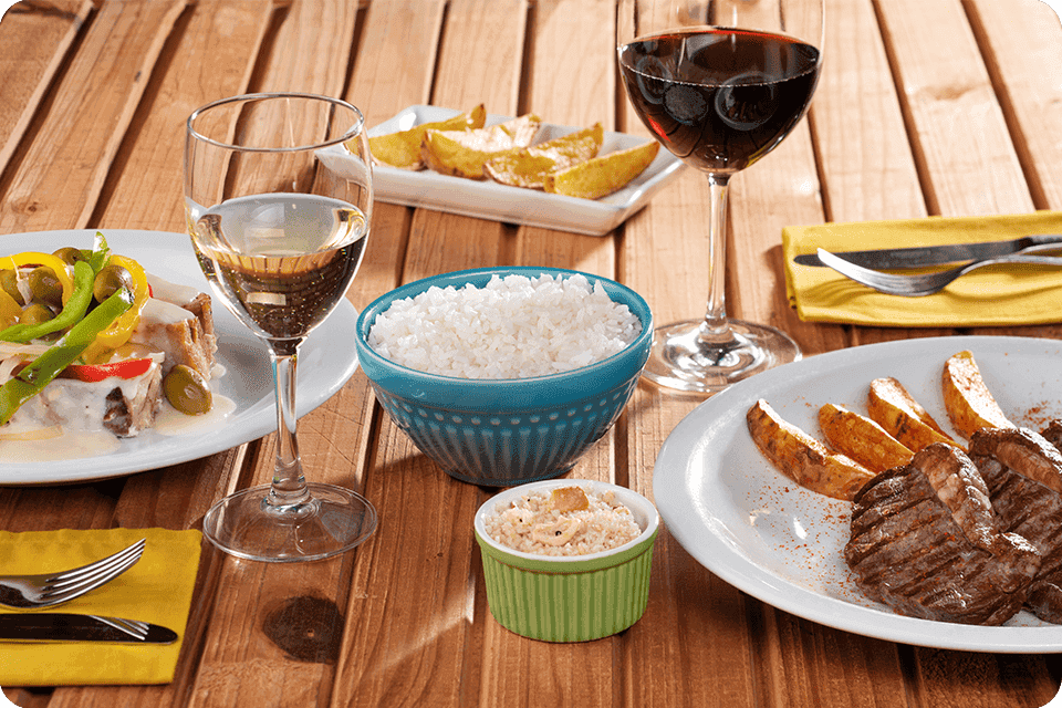 Prato de petiscos com camarão e batata frita e cervejas sobre mesa à beira da piscina do Salinas Maragogi.
