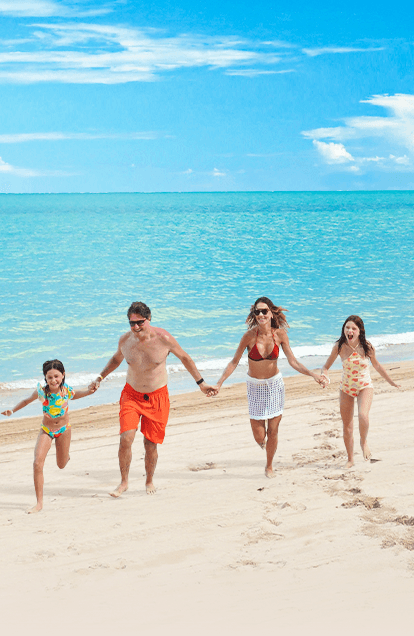 Família feliz aproveita caminhada tranquila na beira mar da praia de Maragogi, próximo ao resort Salinas.