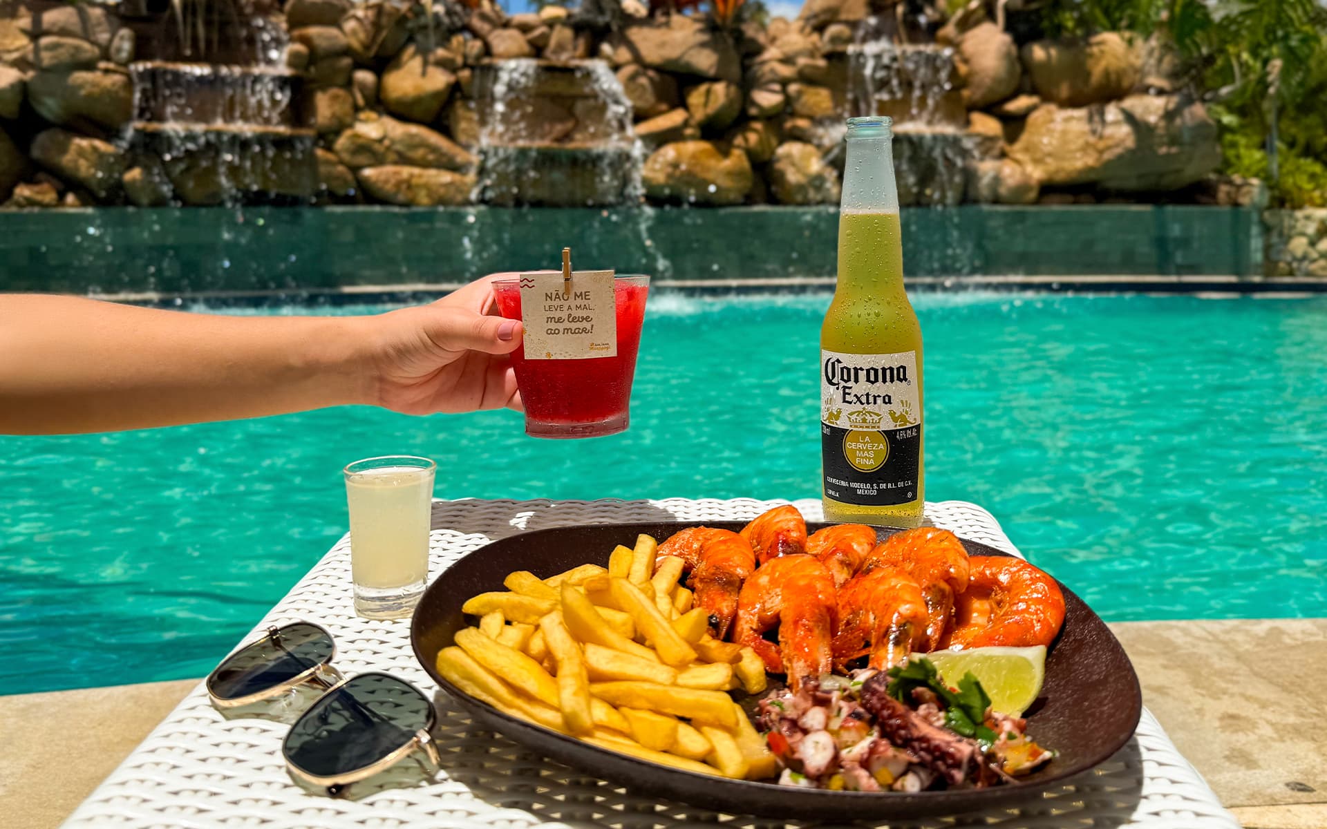 Sabor de férias é imperdível Petiscos e bebidas servidos na piscina do Salinas Maragogi All Inclusive. Com pequenas cachoeiras caindo na piscina com pedras e plantas.
