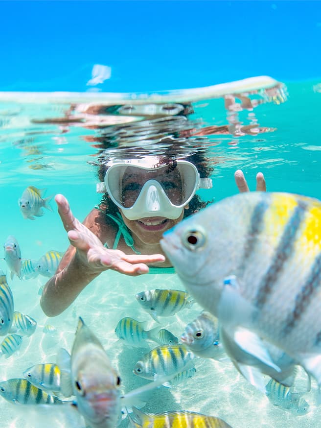 Descobertas nas piscinas naturais de Barra Grande Criança mergulhando nas águas cristalinas de Barra Grande com peixes coloridos ao seu redor.