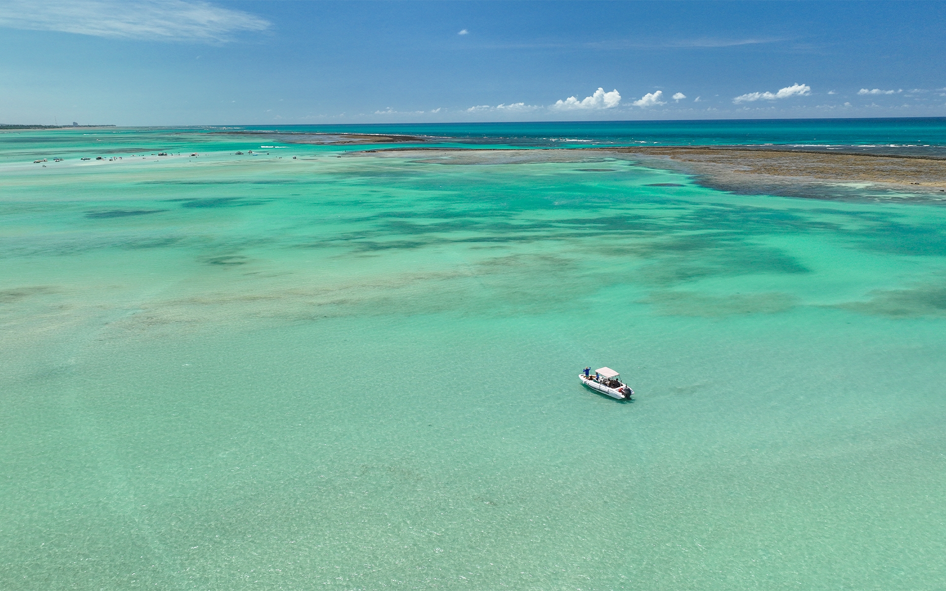 galés-de-maragogi Vista aérea das Galés de Maragogi com lancha na água azul turquesa e recifes de corais ao lado de lancha de passeio.