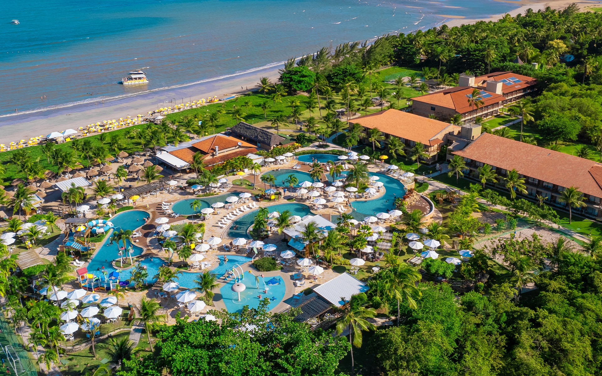 vista-aerea-salinas-maragogi Imagem aérea do Salinas Maragogi mostrando o complexo de piscinas, dos quartos, pontos de consumo e ao fundo a praia. Área verde cercando todo o resort.